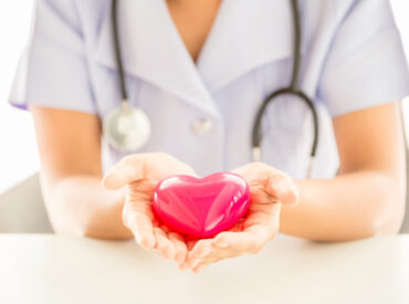 Female nurse with stethoscope holding heart, Healthcare and medical concept.
